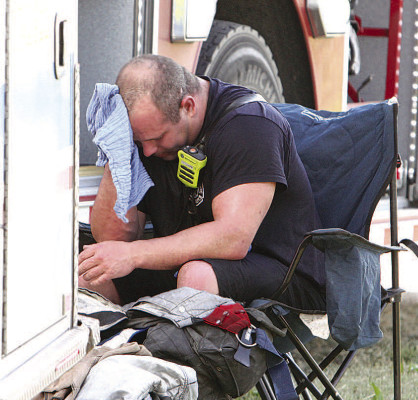A firefighter tries to find some relief from the heat at Sunday’s barn fire. Travis Mounts/TSnews