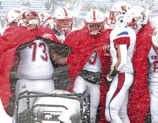 Charlie Daugherty, left, and other members of the Cheney Cardinals warm up in front of heaters before the second-half kickoff on Saturday. Travis Mounts/TSnews