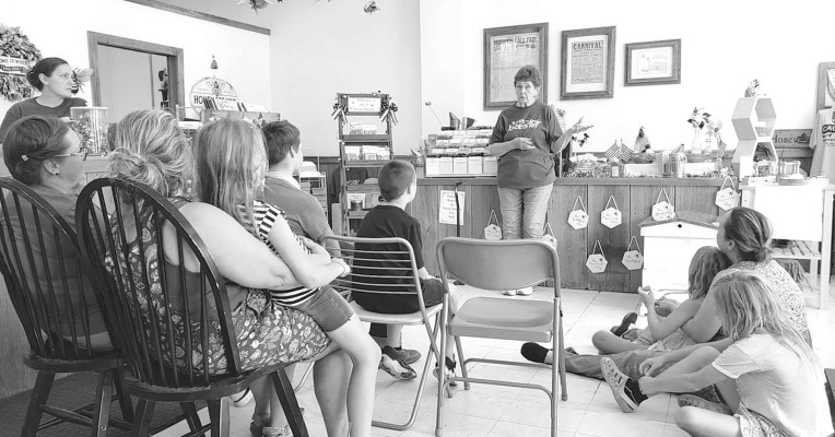 Members of the Conway Springs Cardinals 4H Club sit down at Rowan’s Honey Shop June 23 to learn about how bees make honey, the worker bees, the queen bee, and how they protect the hive.
