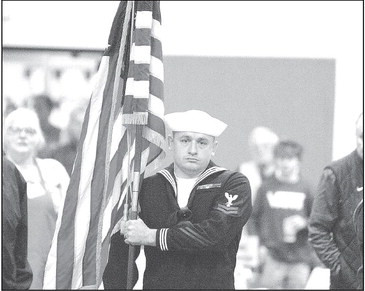 Petty Officer 2nd Class Cory Knight of the United States Navy presents the American flag during last Thursday’s community Thanksgiving dinner in Goddard. A short ceremony was held at the start of the event to honor veterans, including a good number who were in attendance. Travis Mounts/TSnews