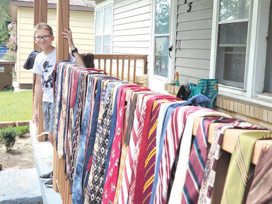 Levi LaPlant shows off the many ties that were for sale at his grandmother Lisa Cash's garage sale over the weekend. The ties had been piling up for a family quilt project, but Cash decided to sell them at her garage sale instead. All proceeds from her sale went to help fund a school trip for her grandson Levi, who also ran a drink stand through the weekend. Paul Rhodes/TSnews