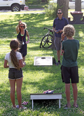 Laura and Johann Reimer play cornhole with their children, Anika and Luka, during the Biking Across Kansas party in Conway Springs’ Central Park. Hundreds of riders spent the night in the city last week on Tuesday Travis Mounts/TSnews