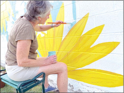 Kelly Caswell works on Cheney’s newest mural, which is located on the north side of Farm Supply. She paints early in the morning to beat the heat. Travis Mounts/TSnews