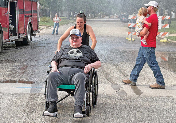 ABOVE: Springview Manor resident Bob Thomas enjoys the spray from the Conway Springs Fire Department during last week’s National Night Out. Springview Manor employee April Curry is assisting him. BELOW: Siblings Madison and Alan Borzek enjoy shaved ice during Goddard’s National Night Out event, which took place last Friday. Contributed photo and Dale Stelz/TSnews