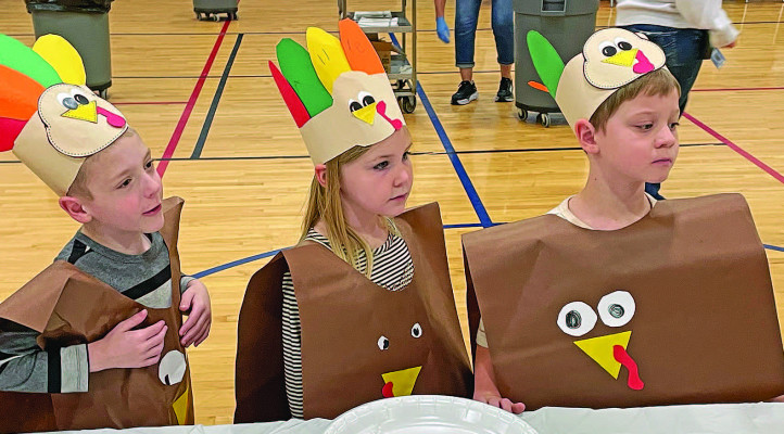 Mark Ramsey, left, Calliope Johnston and Weston Stallbaumer line up to get their food at Oak Street Elementary’s annual Thanksgiving feast. The feast is a decades-old tradition at the Goddard school. Travis Mounts/TSnews