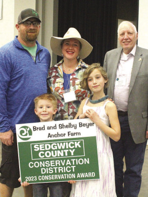 Brad and Shelby Beyer and their children receive their urban conservation award at last week’s Sedgwick County Conservation District meeting and banquet in Wichita. They are pictured with Sedgwick County Commissioner David Dennis. Travis Mounts/TSnews