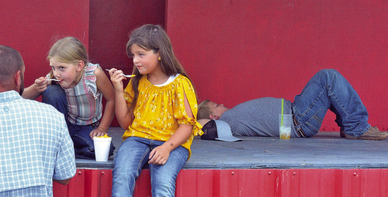 One youth relaxes on the stage as two others enjoy shaved ice on Saturday afternoon at the Sumner County Fair. People from Conway Springs, Argonia and other Sumner County towns gathered in Caldwell for the annual event. See more photos on Page A8. Dale Stelz/TSnews