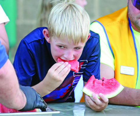 Carter Presnal enjoys a slice of watermelon from the Lions Club at Goddard's National Night out, held on Aug. 8 at Linear Park. National Night Out is a community- building campaign that promotes police-community partnerships and bonds within neighborhoods. Travis Mounts/TSnews