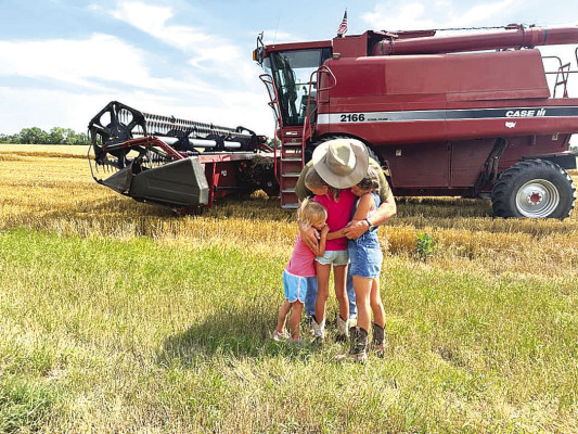Harvest is a family affair. After a day of cutting, Dan Buerki gets a hug from his granddaughters, Jada, Julia and Jenna. The field is located near west Wichita.
